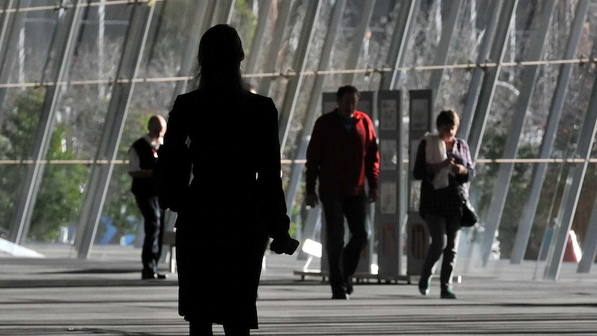 Silhouette of a woman, dressed in a suit, walking on a city street.