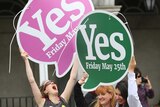 Women hold giant 'Yes' signs in the street