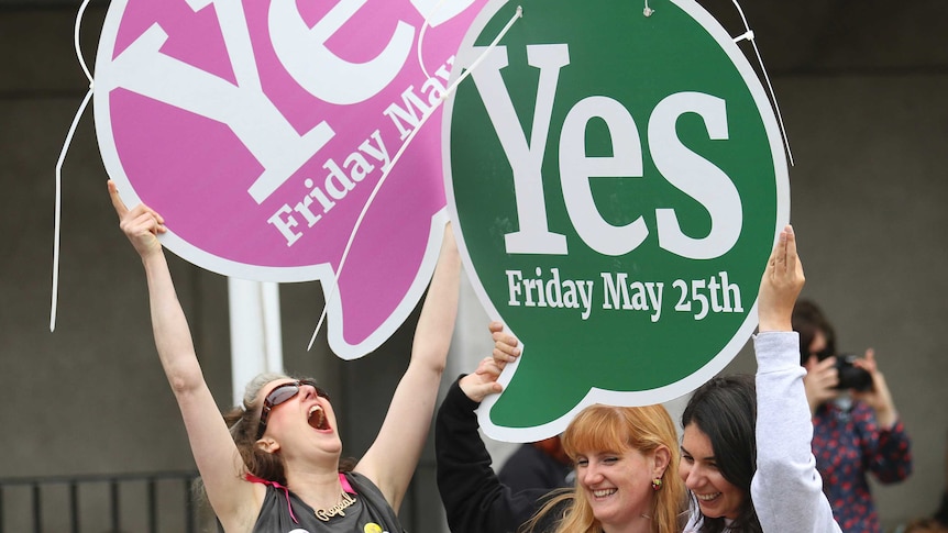 Women hold giant 'Yes' signs in the street