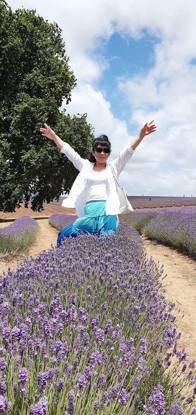 一名女子站在薰衣草丛上方，高举双臂。