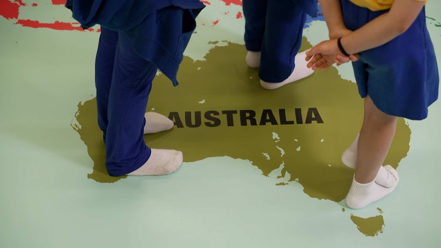 Legs of school kids in uniform standing on a map of Australia