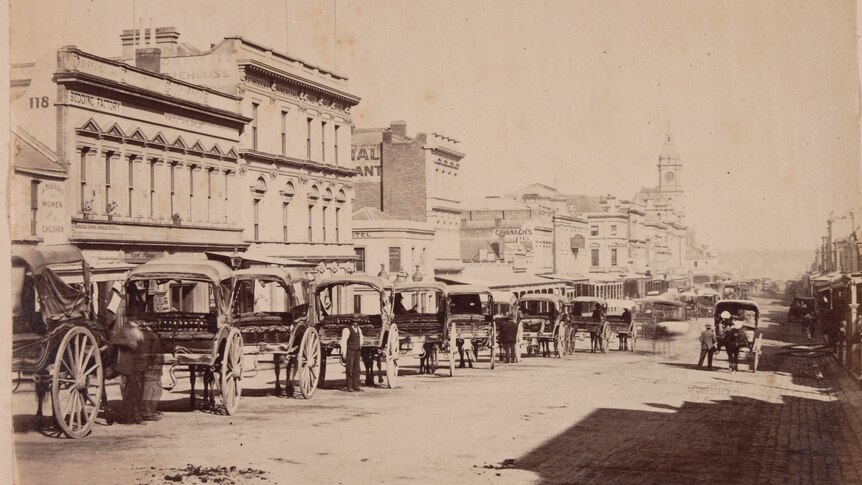 Horse-drawn carriages on the street outside buildings on Swanston St, Melbourne, in 1880.