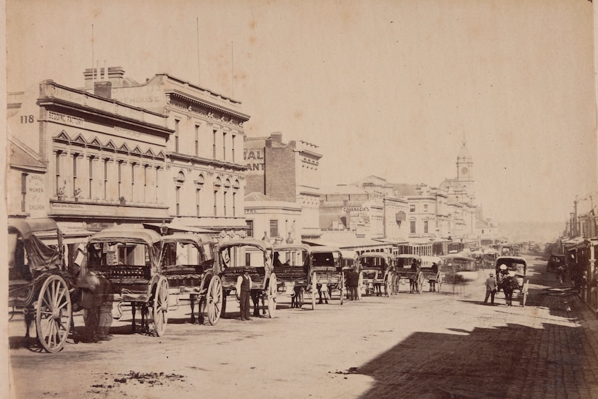 Horse-drawn carriages on the street outside buildings on Swanston St, Melbourne, in 1880.