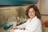 Woman wearing science goggles smiles at the camera.