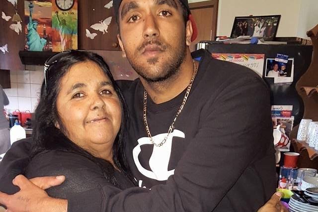 Francina Wynne hugs her son Kyrone Eades while standing indoors and posing for a photo.