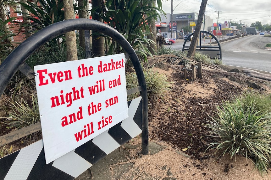 A sign says "Even the darkest night will end and the sun will rise".