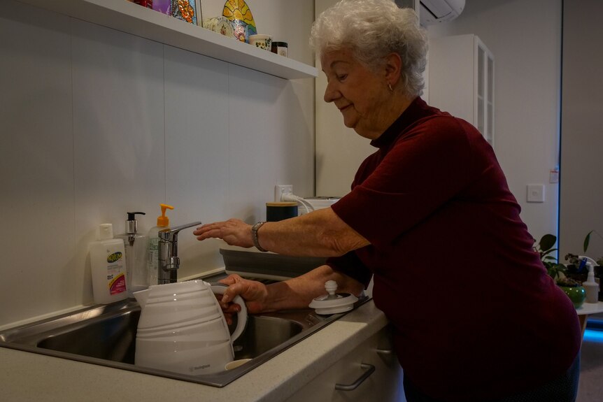 A woman filling up a kettle. 