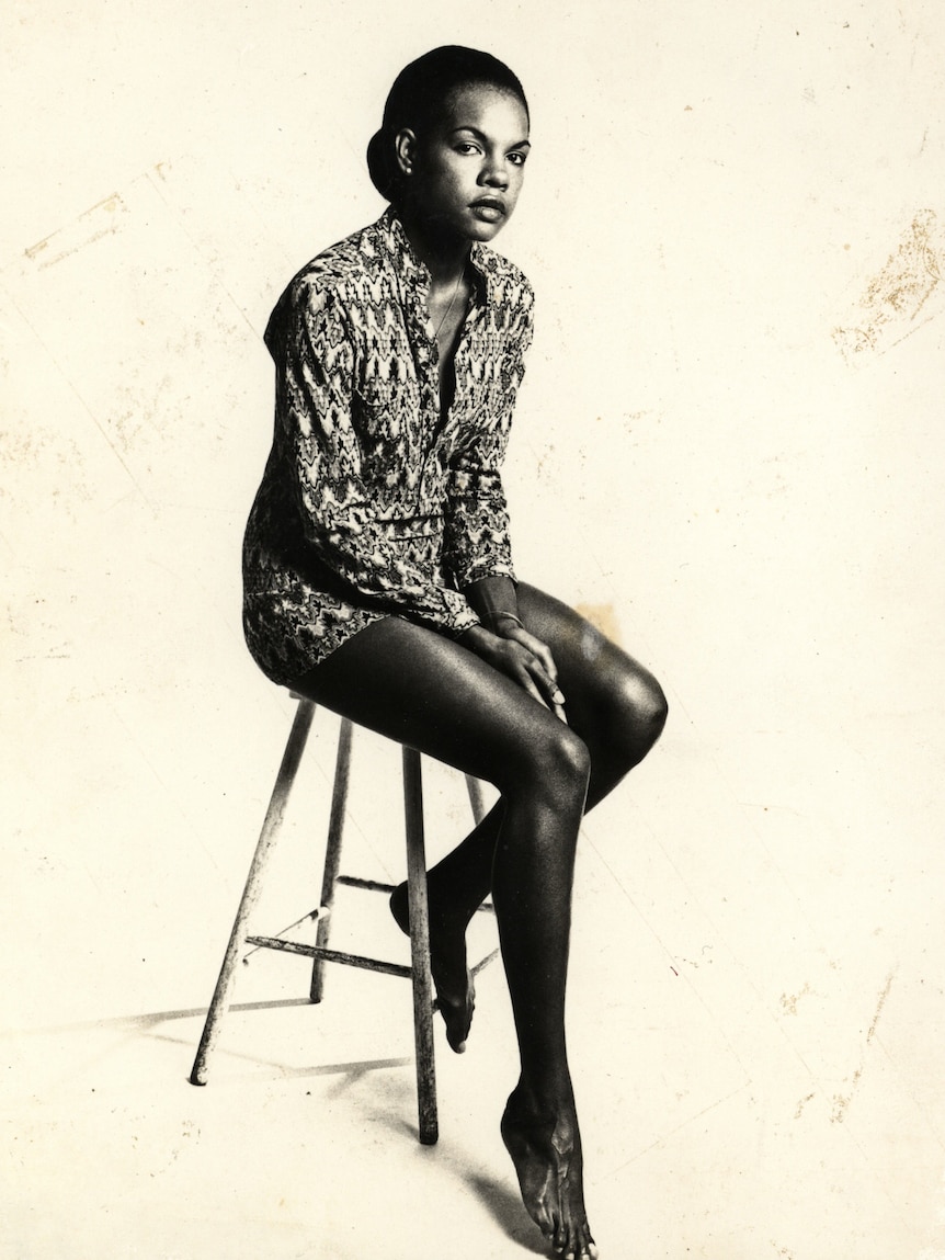 A woman model sitting on a stool.