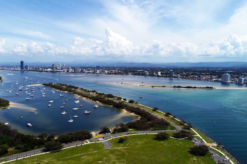 A body of of water near a city with buildings in the background and green space in the foreground