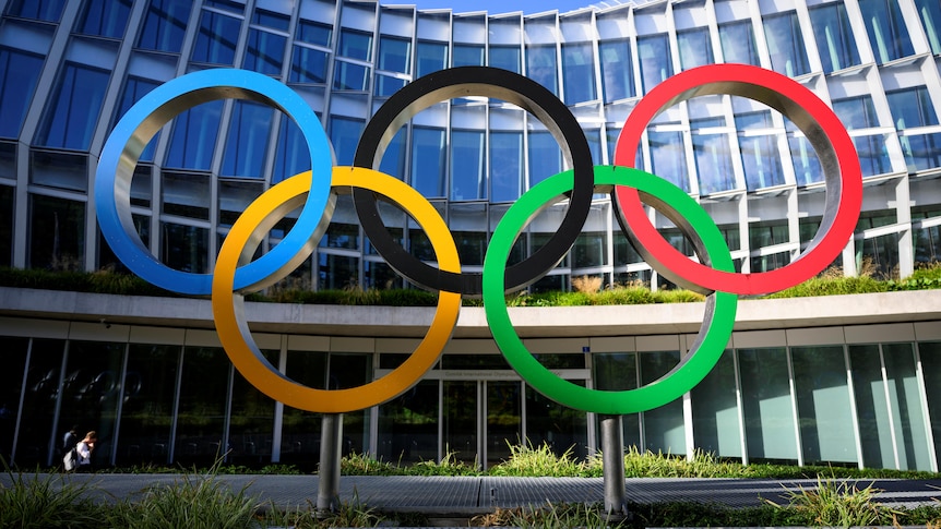 The Oympic rings in front of a building. 