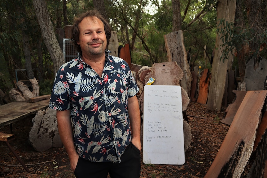 Man standing with timber cuttings behind him.