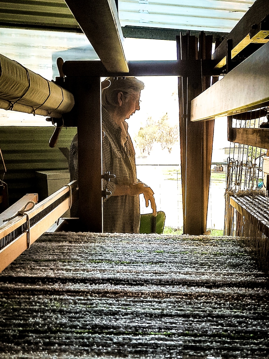 woman standing in middle of loom