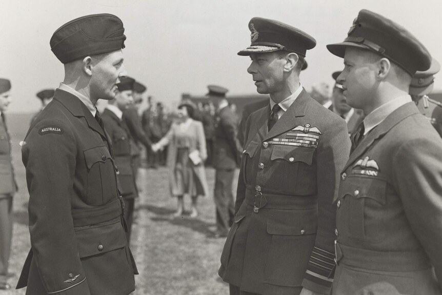 A black and white photo of an Australian Air Force aviator being congratulated by the King.