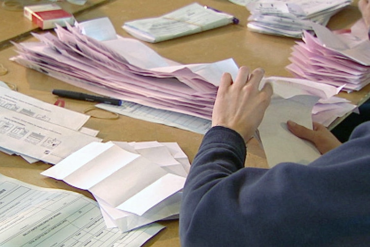 A person counting ballot papers in a WA election.
