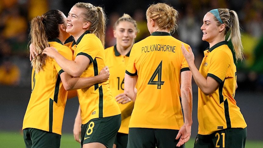 Five Matildas players celebrate after beating Brazil.