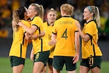 Five Matildas players celebrate after beating Brazil.