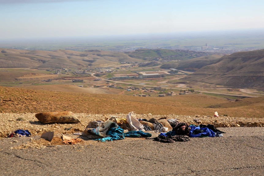 Yazidi clothes lay scattered on the road overlooking Sinjar were thousands fled IS forces