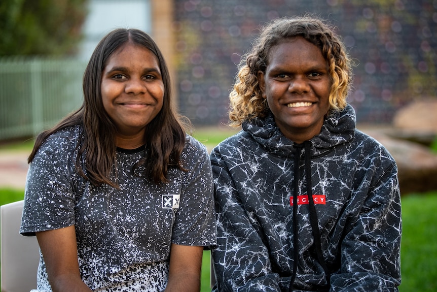 Two young Aboriginal girls sitting next to each other
