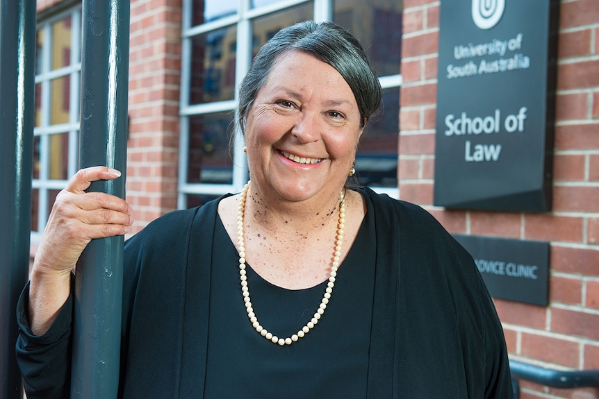 An Aboriginal woman wearing a black shirt and necklace in front of a building