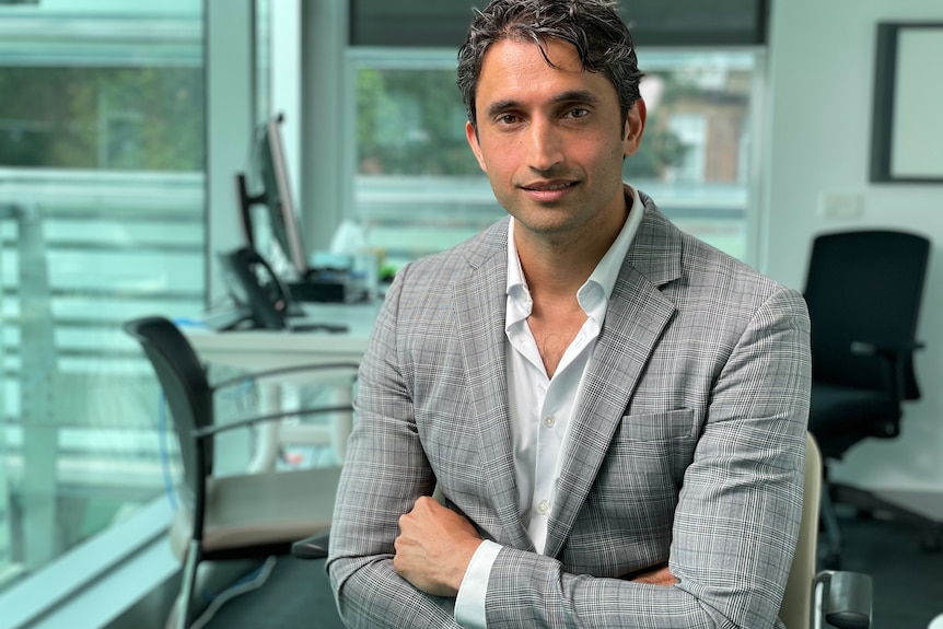 Man sitting in an office with his arms folded.