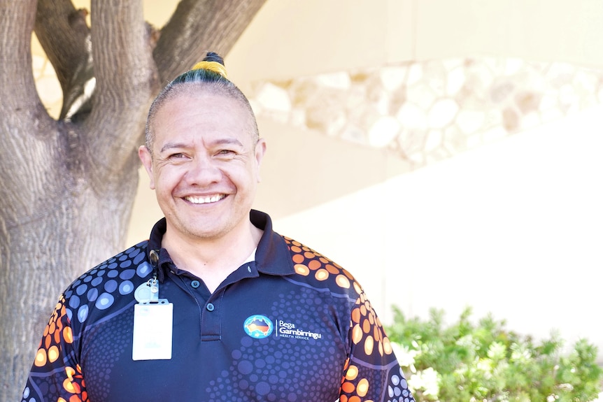 A kiwi man with top knot and a big smile 