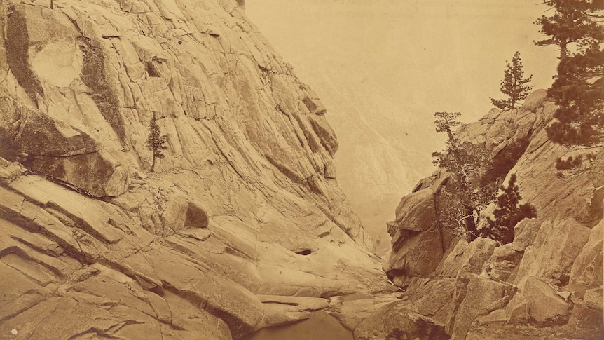 sepia-toned photograph of a v-shaped rock formation dropping away to a valley below