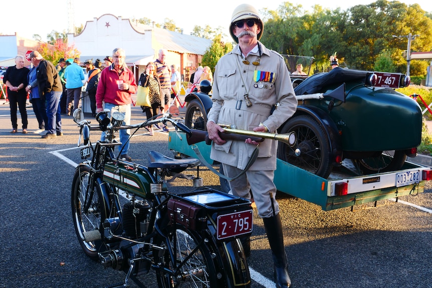 A man dressed as a 19th century hunter poses with raygun and vintage motorbike.