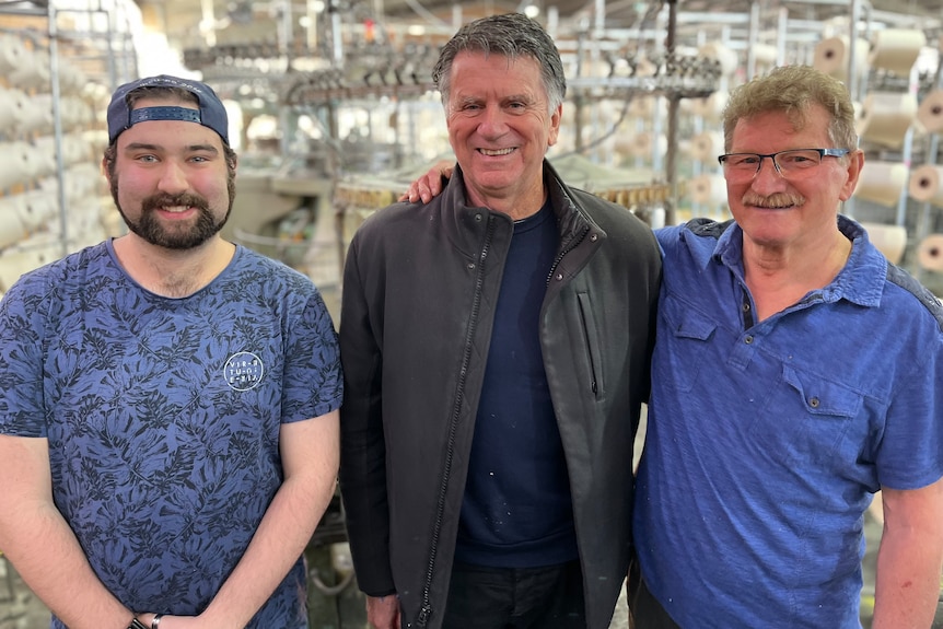 Three men stand side-by-side smiling.