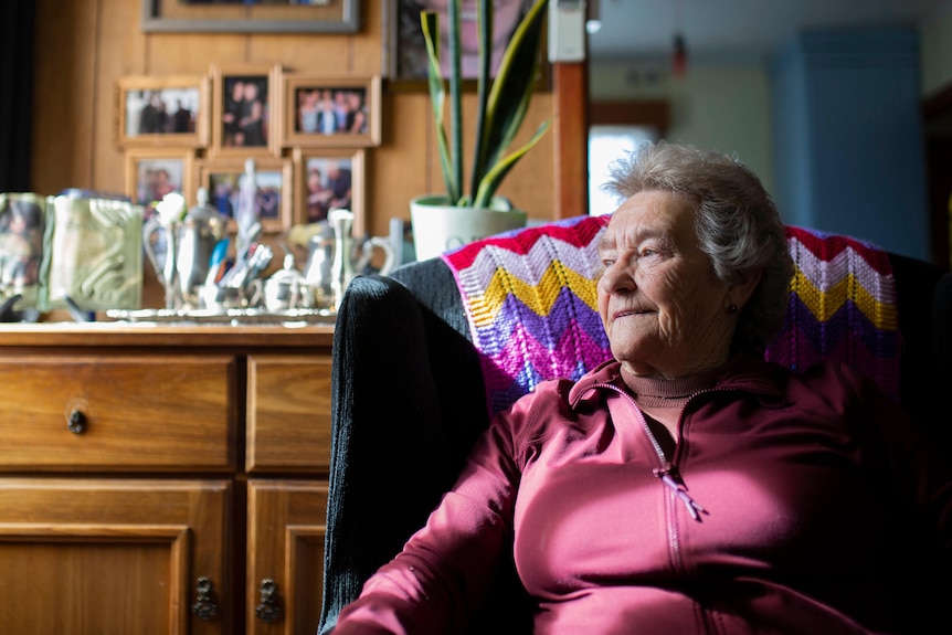 An elderly woman sits on a chair