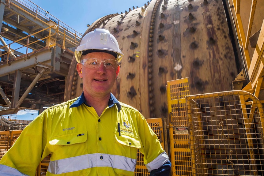 A man wearing high-vis workwear and safety glasses on a mine site.