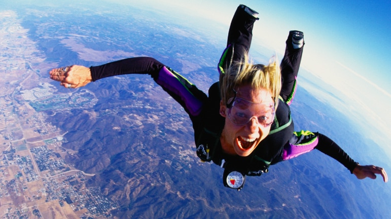 A woman screams with excitement during a sky dive.