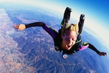 A woman screams with excitement during a sky dive.