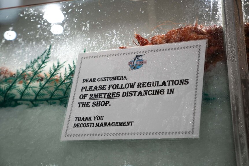 sign says please follow regulations of 2 metres distancing in this shop