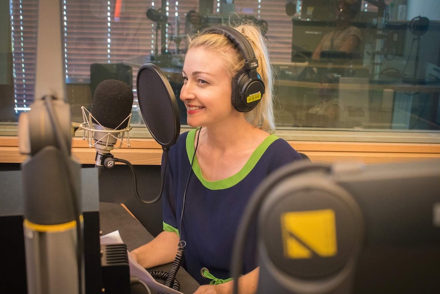 Kate in radio studio wearing headphones speaking into microphone.