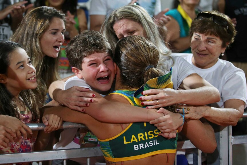 Larissa of Brazil embraces her family members after the women's beach volleyball quarterfinal.
