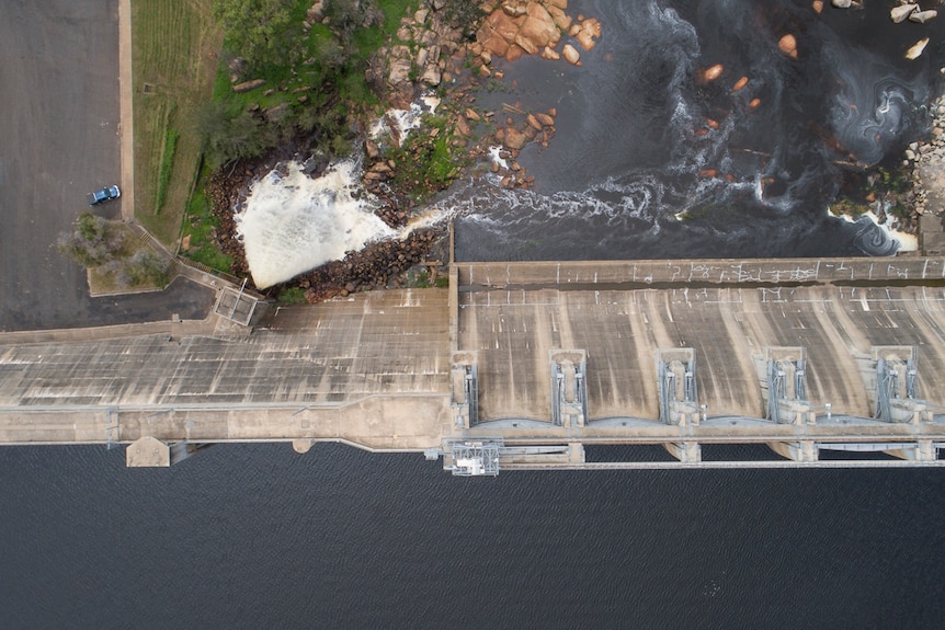 Aerial photo of water gushing from a dam and down a creek.