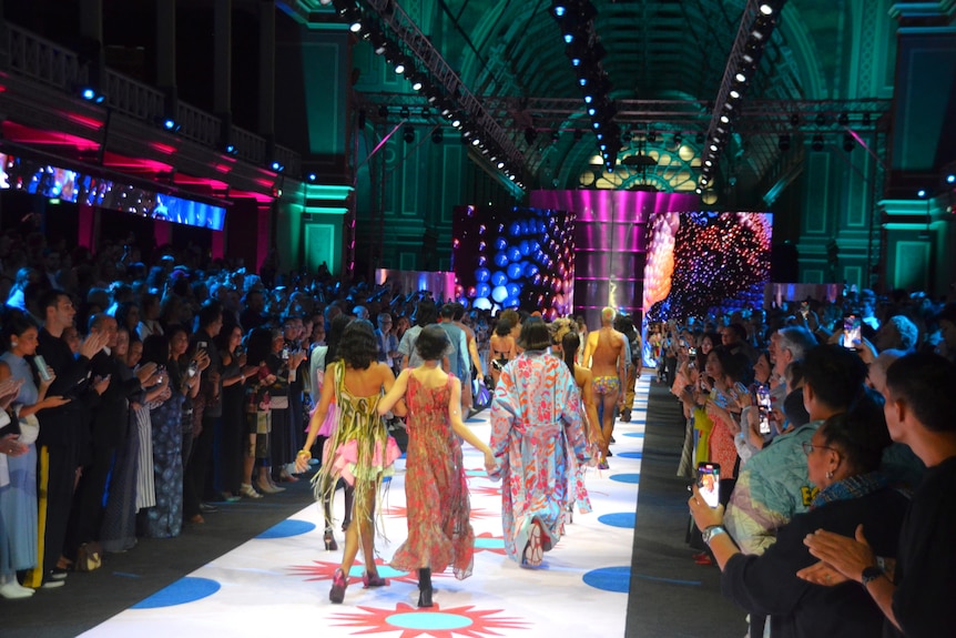 Models in colourful dresses are strutting back down the runway as a group to finish the show