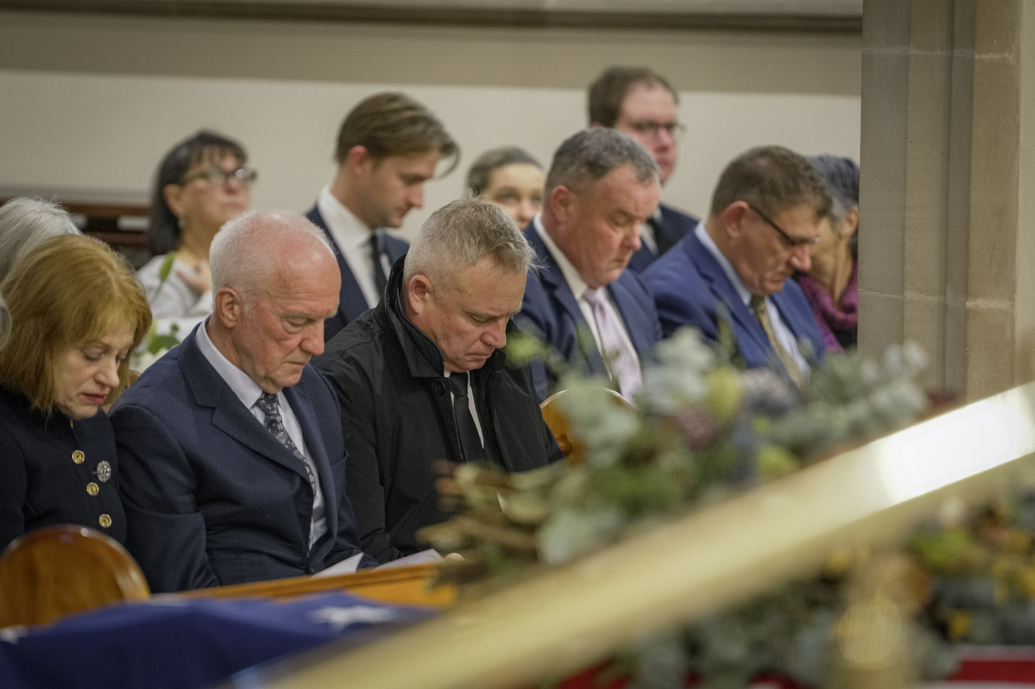Barbara Baker, Don Chalmers and Jeremy Rockliff sit next to each other in a church pew.
