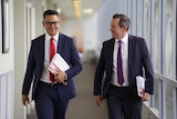 Treasurer Ben Wyatt and Premier Mark McGowan walking along smiling and carrying budget papers.