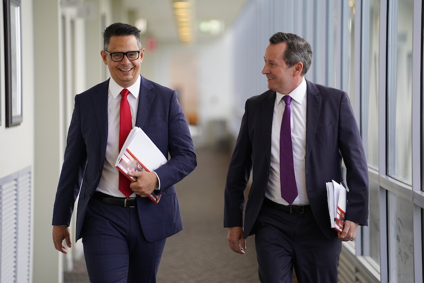 Treasurer Ben Wyatt and Premier Mark McGowan walking along smiling and carrying budget papers.