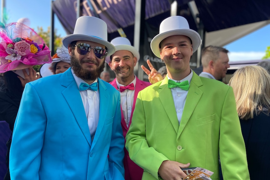 Three men in blue, green and pink suits.