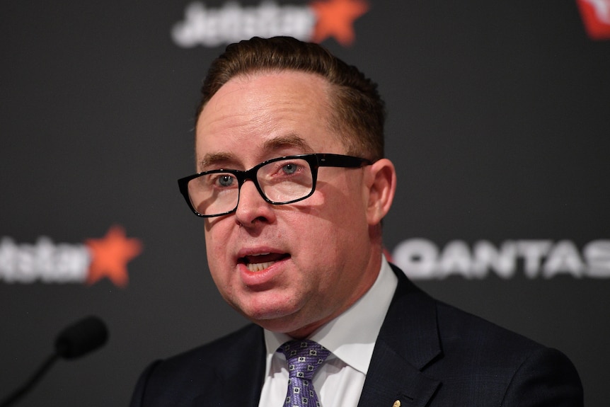 A close up of Alan Joyce pictured in front of a Qantas backdrop