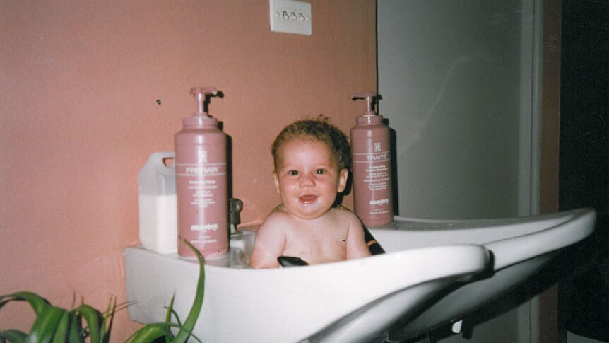 Baby Ross takes a bath in a salon basin.