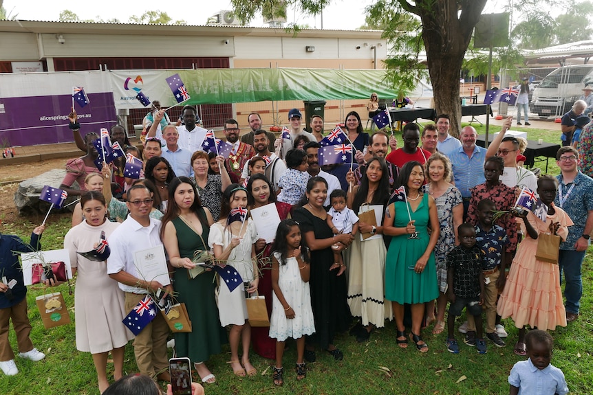 A group of people standing together with some holding Australian flags.
