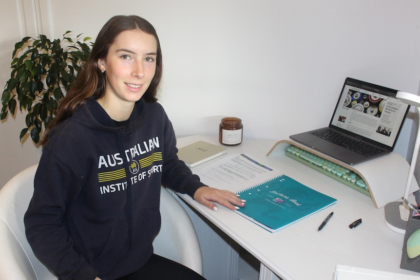 She wears a hoodie and sits at a computer