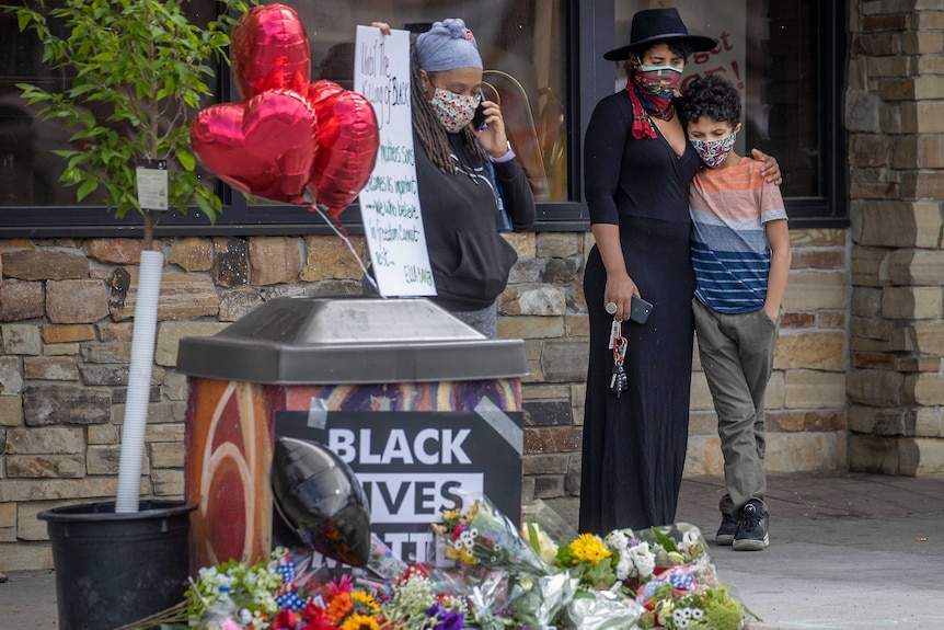 A mother holds her son close as she stood to pay respect at a memorial on the street side.