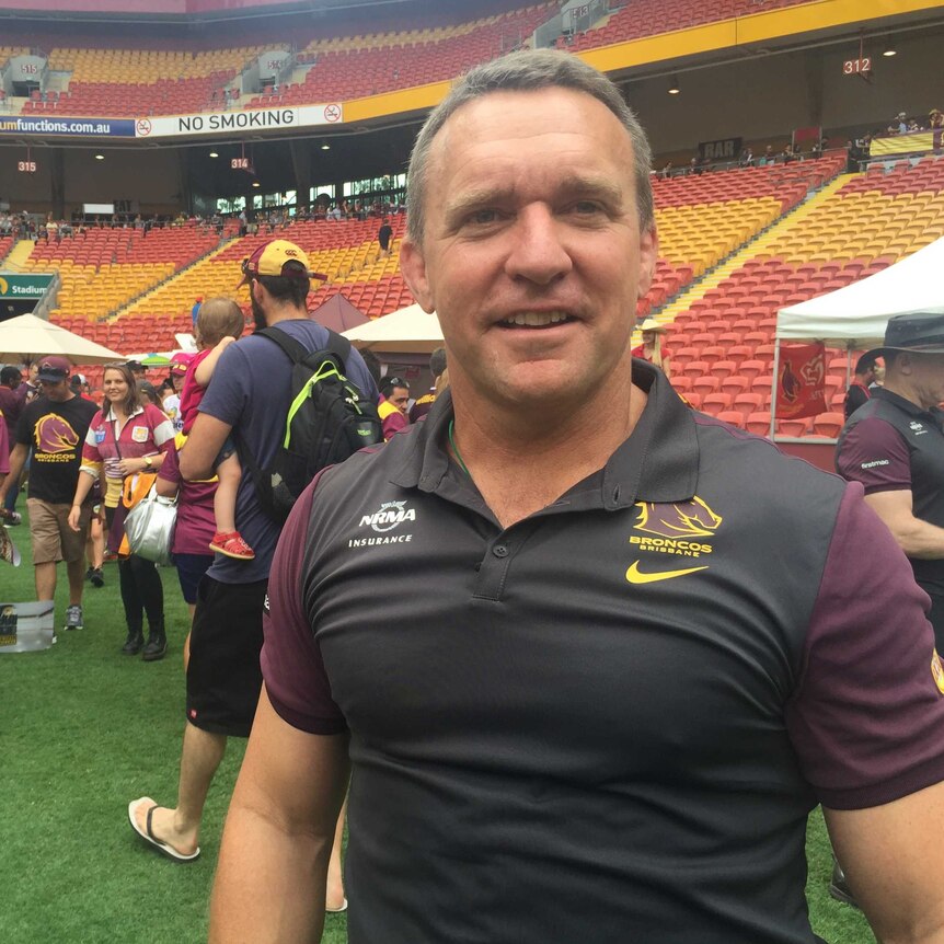 Paul White stands on the field at Suncorp Stadium with fans and seats behind him