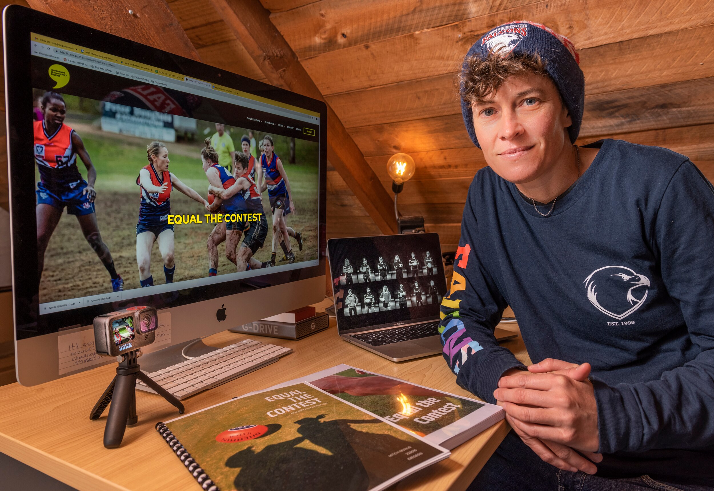 A person sitting in front of a work desk with multiple screens, one of which says 'Equal the Contest'.
