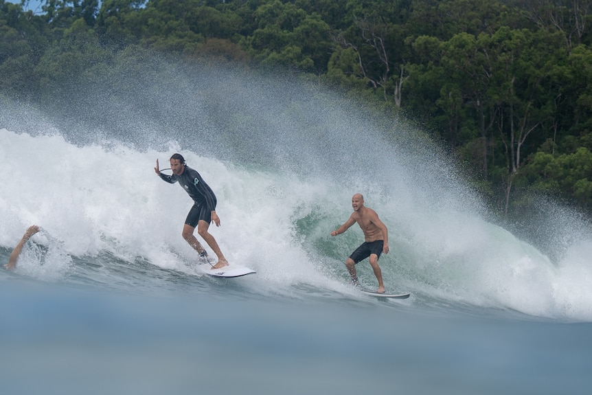 Two surfers ride the same wave in Noosa