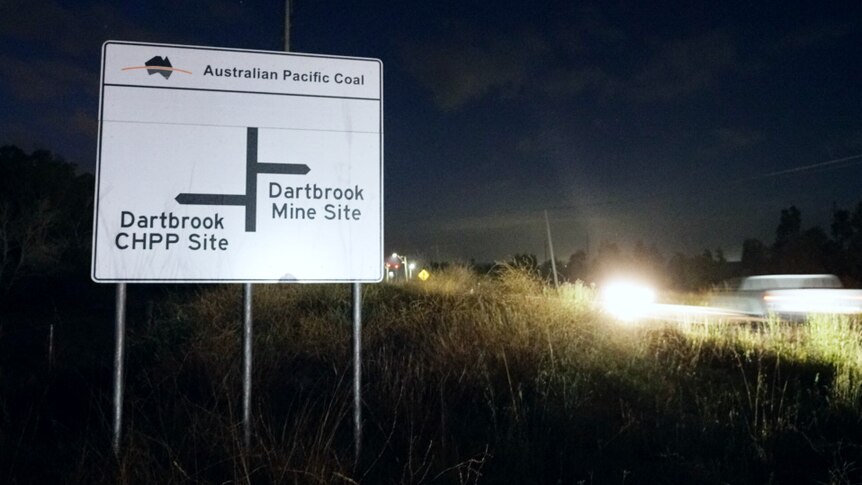 A road sign showing where the Dartbrook mine site is at night with cars going past blurred.